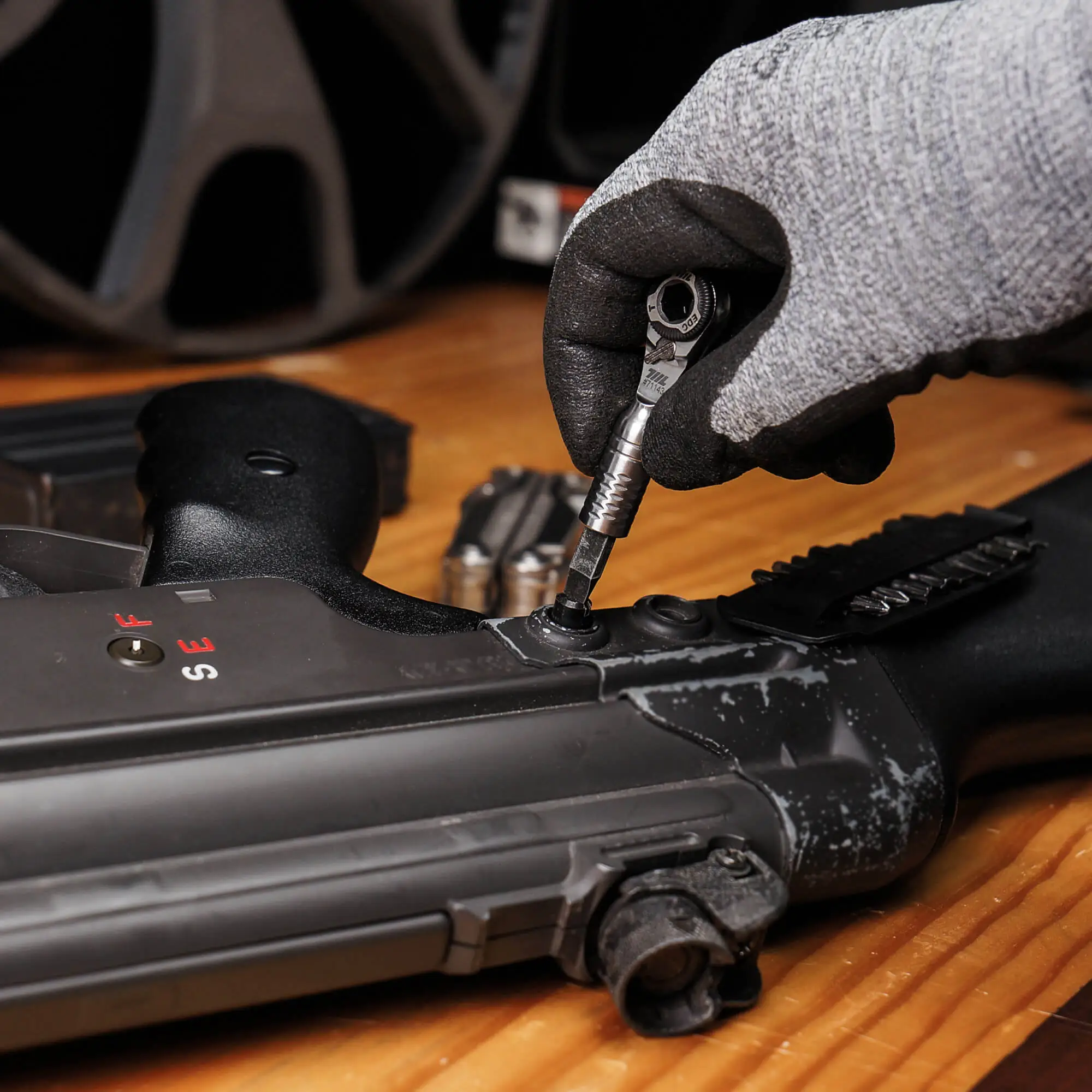 Gloved hand using the 711L Mini Ratchet Wrench TG to tighten a screw on a metal assembly